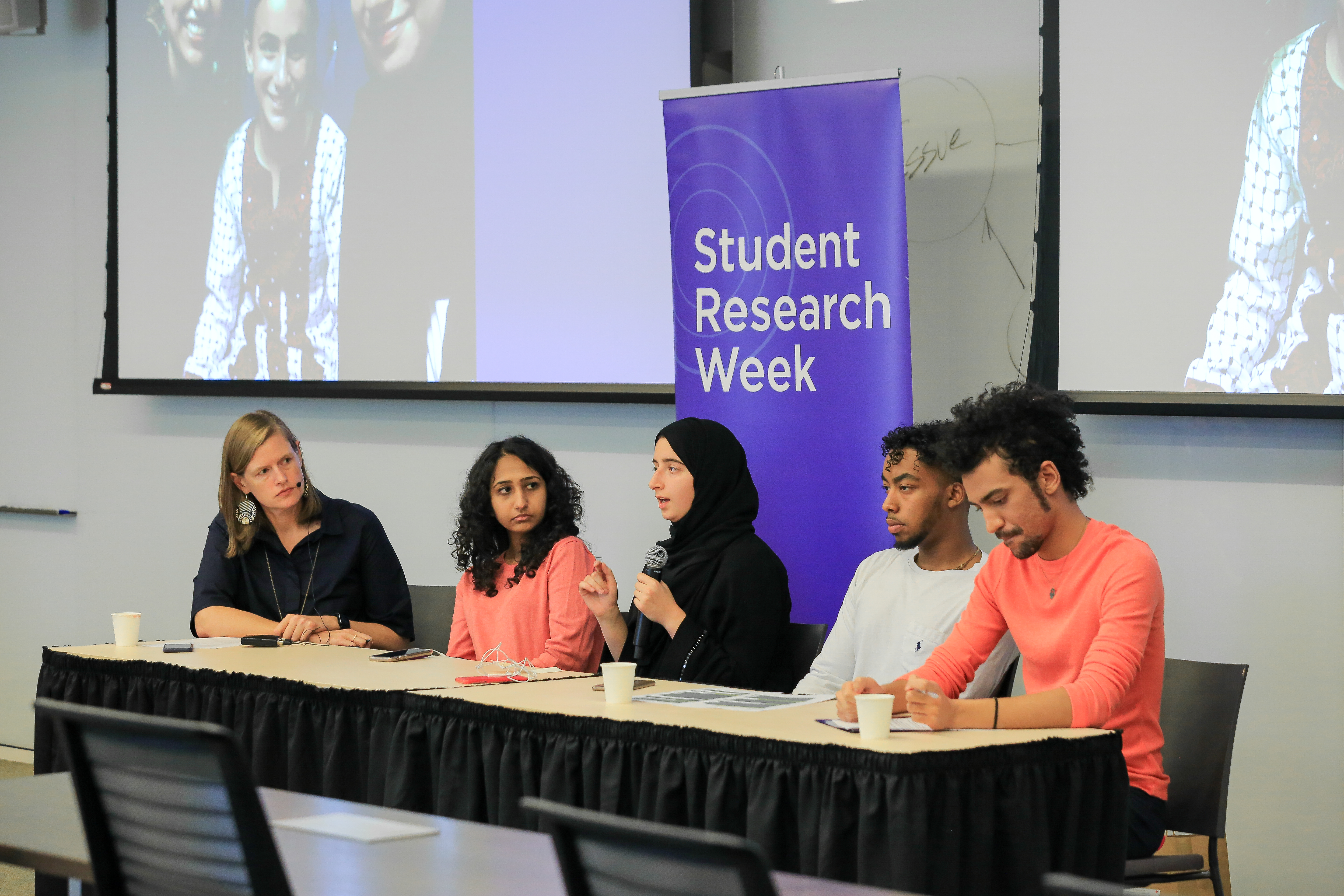 NU-Q students presenting their research in a moderated discussion during a community event