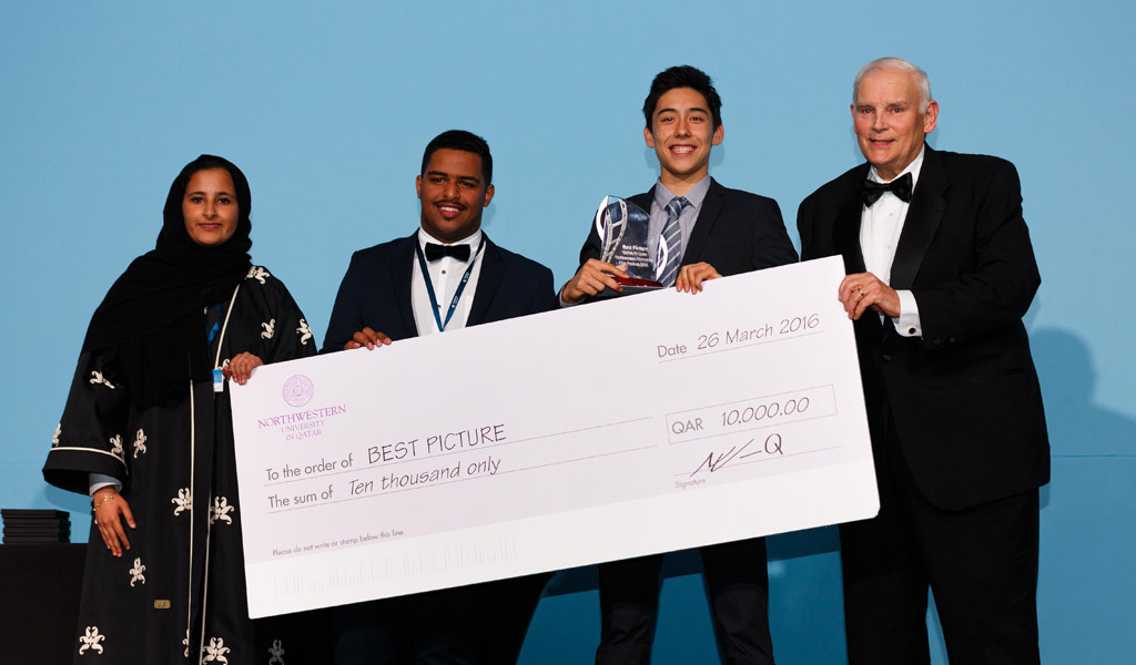 Dean and CEO of NU-Q Everette E. Dennis presents award to the winner of the Best Picture Award: Daniel Kai Shen, Taipei American School, Taipei City, Taiwan for “Our Art, Our Voices.” Joining them on stage are Qatar Academy students Maryam Al-Khalifa and Ahmed Al Hajri.