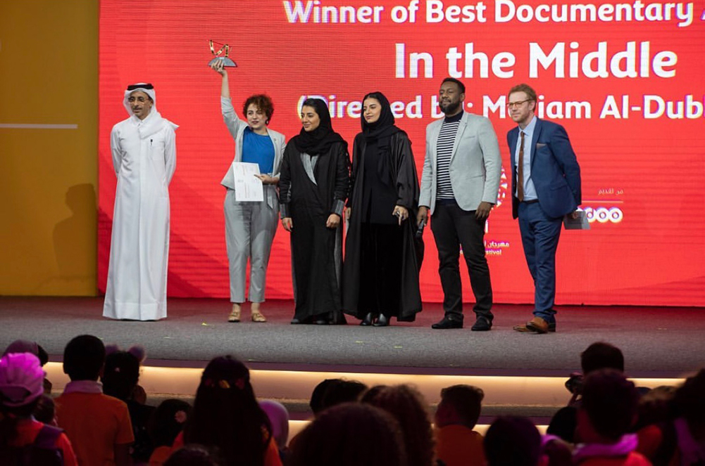Mariam Al-Dhubhani, NU-Q alumna '18 and director of "In the Middle" receives her award for Best Documentary during the Ajyal closing ceremony. Al-Dubhani (second from the left) is accompanied by representatives from DFI, Ooredoo Qatar, filmmaker Amjad Abu Alala, and HE Salah bin Ghanem Al Ali, Minister of Culture and Sports (far left).  Photo credit: Ooredoo Qatar