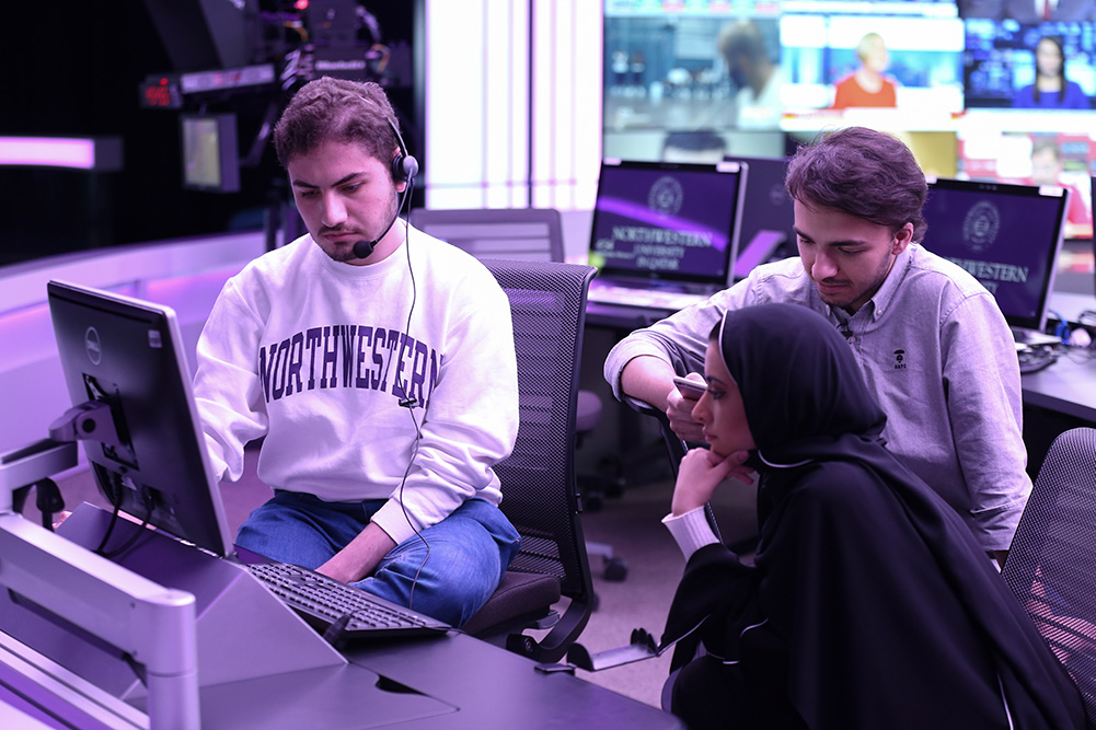 Northwestern Qatar students Ayman Al Rashid (left), Muaaz Dembinski, and Jawaher AlMoawda working together in the Newsroom, where journalism students learn to report and produce news shows.